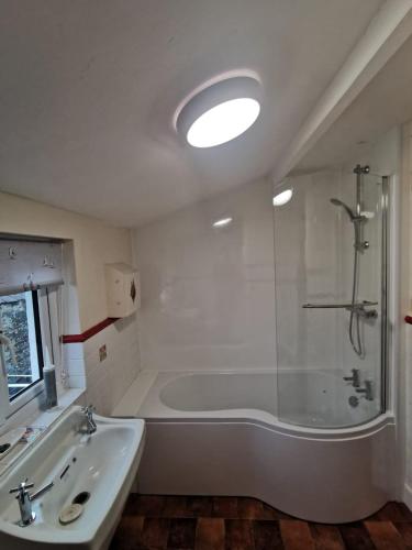 a white bathroom with a tub and a sink at Large farmhouse in Snowdonia, North Wales in Talsarnau