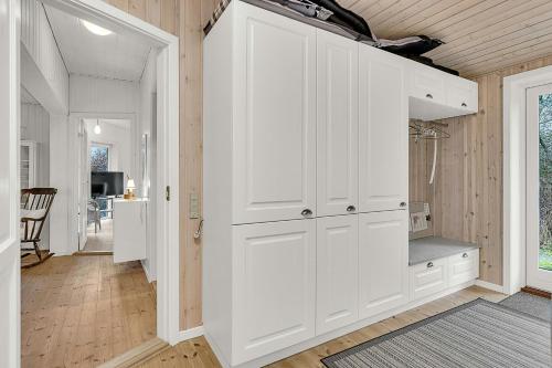 a white kitchen with a large white cabinet at Holiday Home By Gudenå River With Natural Garden in Bjerringbro