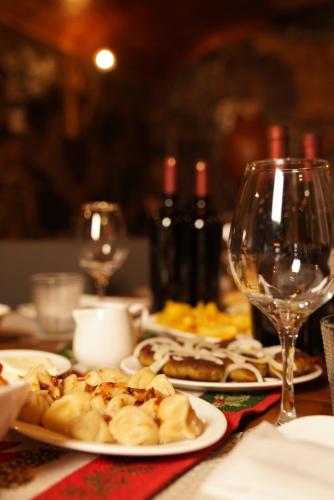 a table topped with plates of food and wine glasses at Hotel Hobbiton near Vardzia Caves in T'mogvi