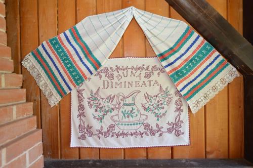 a quilt hanging on a wooden wall with a door at Casa de Piatră - Colț de Rai in Arieşeni