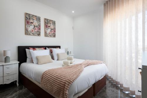 a bedroom with a bed with white sheets and a window at Espadarte - Sea view by HD in Quarteira