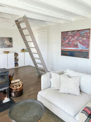 a living room with a white couch and a staircase at Romantic Country Cabin With Fjord Views On Åmøy in Stavanger