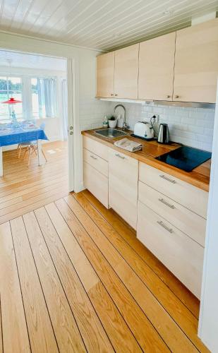 a kitchen with white cabinets and a wooden floor at Serene Waterfront Oasis Your Resarö Sanctuary in Vaxholm