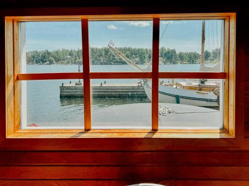 a window with a view of a boat in the water at Serene Waterfront Oasis Your Resarö Sanctuary in Vaxholm