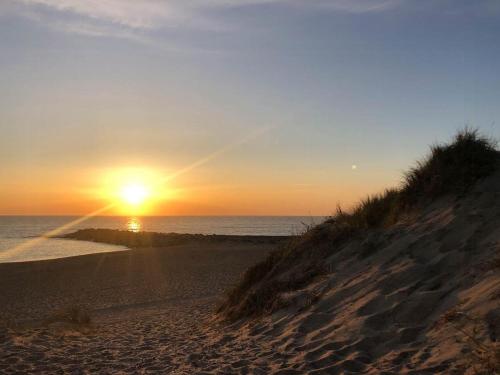 a sunset on a beach with the sun setting over the ocean at Holiday Home With Sea Views Over The Western Sea in Vestervig