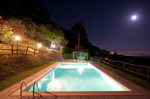 a swimming pool at night with the moon in the background at Villa With Views Over Lucca Hills in Matraia