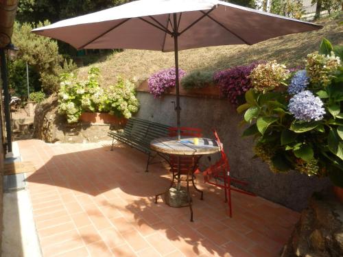 a table with an umbrella and a bench with flowers at Villa With Views Over Lucca Hills in Matraia