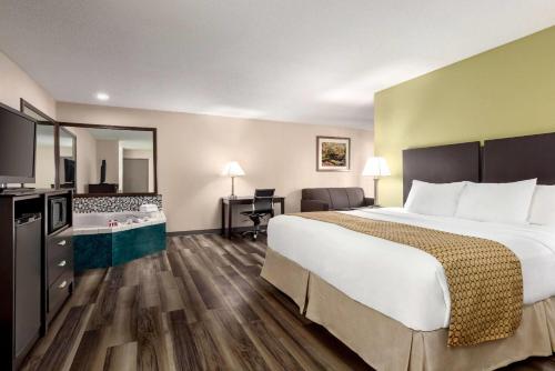 a hotel room with a large bed and a desk at Baymont by Wyndham Monroe in Monroe