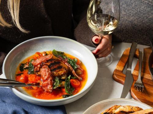 a bowl of food on a table with a glass of wine at Hotel Alba Adelaide in Adelaide