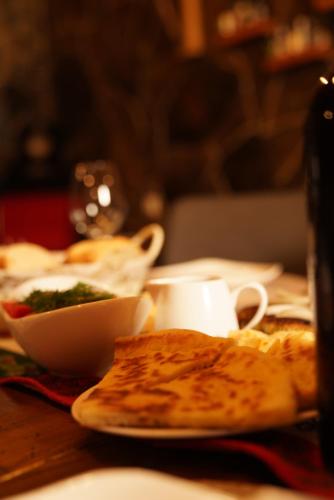 a table with a plate of pizza and a bowl of food at Hotel Hobbiton near Vardzia Caves in T'mogvi