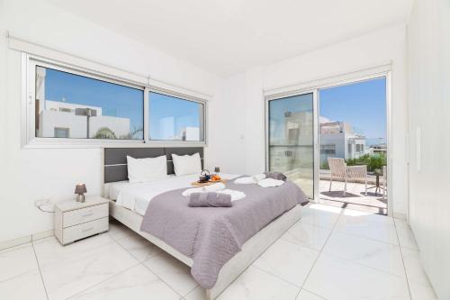 - une chambre blanche avec un grand lit et de grandes fenêtres dans l'établissement Elite Blu Heights Villa, à Ayia Napa