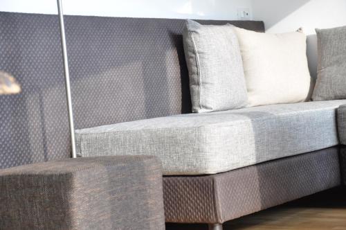 a gray couch with a white pillow and a stool at Alpenchalet Apartments in Parcines