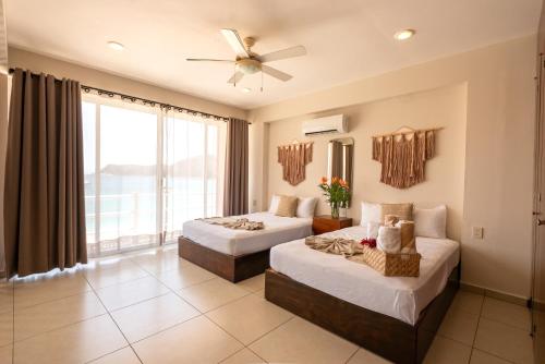 a bedroom with two beds and a large window at La Playa Suites in Santa Cruz Huatulco