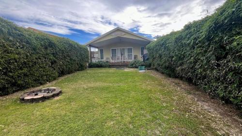 a house with a lawn in front of a hedge at Sandy Feet in Wooli