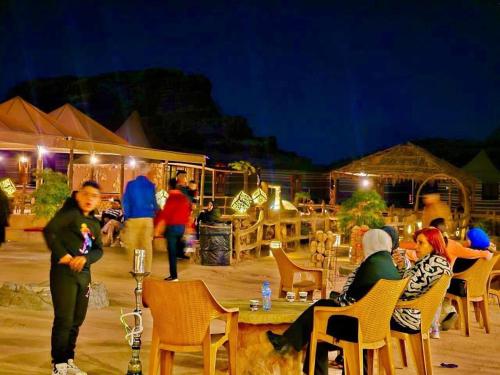 a group of people sitting at a table at night at Wadi Rum Santa Camp in Wadi Rum