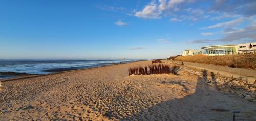 a sandy beach next to the ocean with a building at Hotel Meereswoge in Cuxhaven