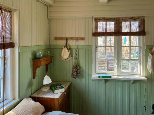 a bedroom with green walls and a bed and windows at Thatched Cottage Between Tisvilde And Liseleje in Frederiksværk