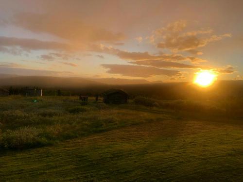a sunset over a field with a barn in the distance at Historic Log Cabin With Views Of Rondane in Ringebu