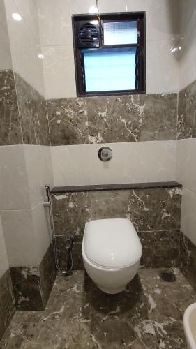 a bathroom with a toilet and a window at Hotel Grand Lushwood in Aurangabad