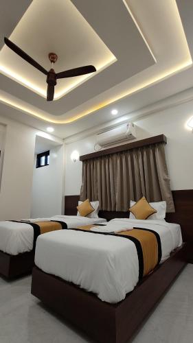 two beds in a hotel room with a ceiling fan at Hotel Grand Lushwood in Aurangabad