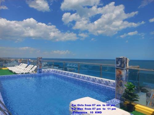 a swimming pool with a view of the ocean at Blue Waves Hotel Abu Halifa أمواج الخليج الزرقاء أبو حليفة in Kuwait
