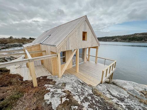 a wooden house on the shore of a body of water at Architectural Gem On Rocks In Kvenvær in Kvenvær