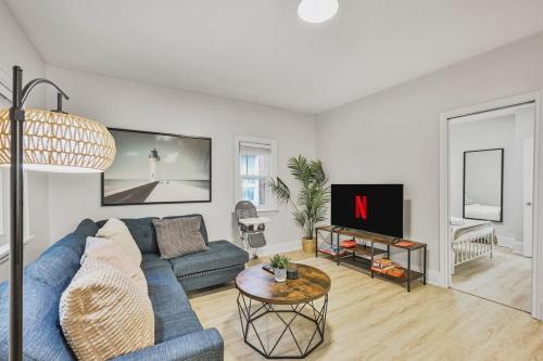 a living room with a blue couch and a tv at Chic 2 BR Urban Retreat Near Beach Free Parking in Oshawa