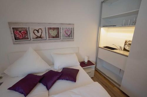 a bedroom with a white bed with purple pillows at Appartements am Markt in Greifswald