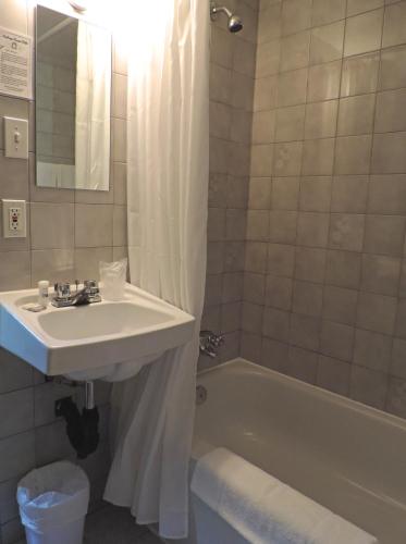 a bathroom with a sink and a bath tub at Auberge Centre Ville in Saguenay