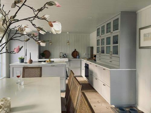 een grote keuken met witte kasten en een tafel bij Modern Summer House With Pool In Risør in Risør