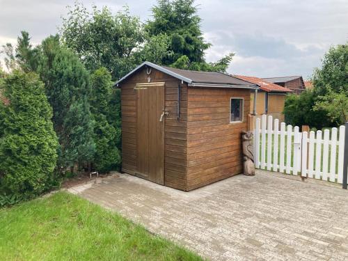 a wooden shed with a white fence in a yard at Ferienhaus Pusteblume in Halberstadt