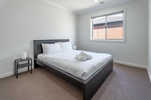 a bedroom with a bed with white sheets and a window at Spacious Family Retreat 4BR Home Parks Zoo Golf in Wyndham Vale