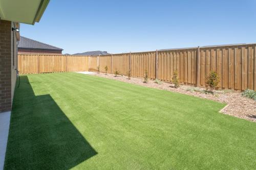 a backyard with a fence and a green lawn at Spacious Family Retreat 4BR Home Parks Zoo Golf in Wyndham Vale