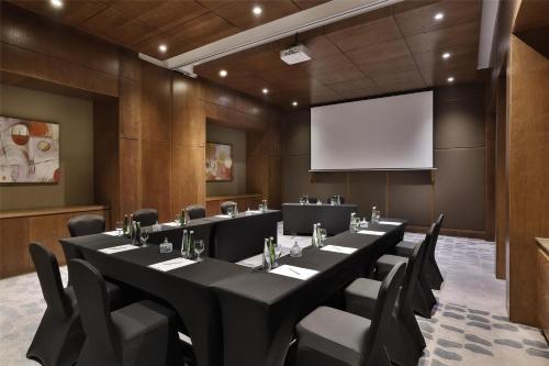 a conference room with tables and chairs and a screen at DoubleTree by Hilton Resort & Spa Marjan Island in Ras al Khaimah