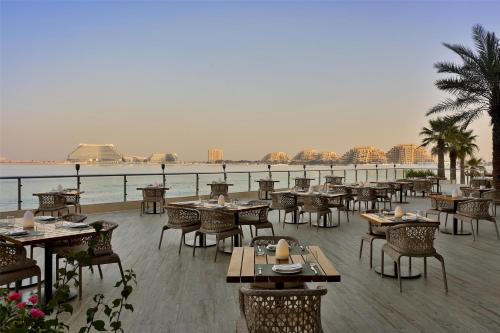 a restaurant with tables and chairs and a view of the water at DoubleTree by Hilton Resort & Spa Marjan Island in Ras al Khaimah
