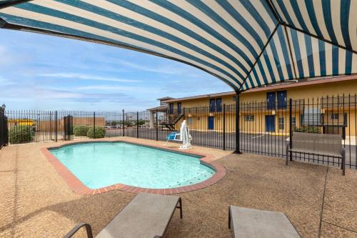 a pool with awning and benches next to a building at Travelodge by Wyndham New Braunfels in New Braunfels