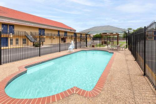 a swimming pool with a fence and a woman walking by it at Travelodge by Wyndham New Braunfels in New Braunfels