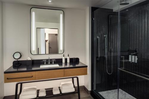 a bathroom with a sink and a shower with a mirror at Canopy By Hilton Nashville Downtown The Gulch in Nashville