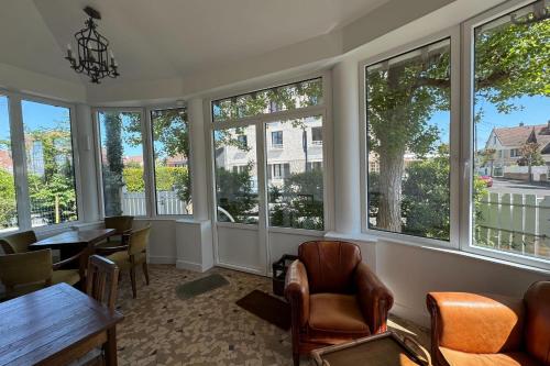 une pièce avec des fenêtres, une table et des chaises dans l'établissement Family house by the sea, à Ouistreham