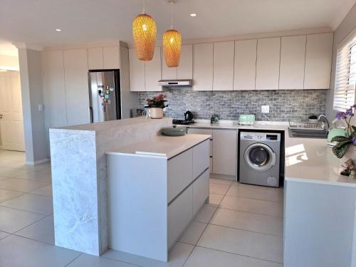 a kitchen with white cabinets and a washer and dryer at West Coast Rock in St Helena Bay