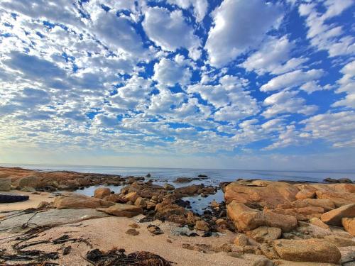 a beach with rocks and a cloudy sky at West Coast Rock in St Helena Bay