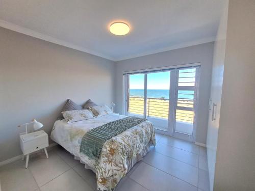 a bedroom with a bed and a view of the ocean at West Coast Rock in St Helena Bay