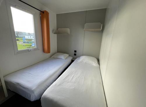 two beds in a small room with a window at Vakantiepark Klein Strand - Comfort Chalet 4p in Jabbeke