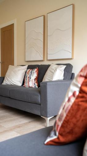 a gray couch with pillows in a living room at Curtis Apartment in Glasgow