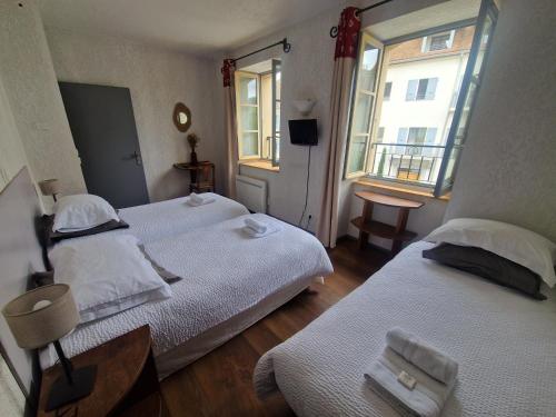 two beds in a small room with two windows at L'Auberge de Mens in Mens