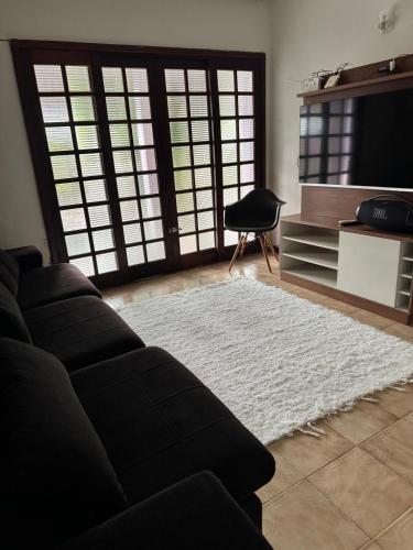 a living room with a black couch and a white rug at Home in Guapimirim for Family in Guapimirim