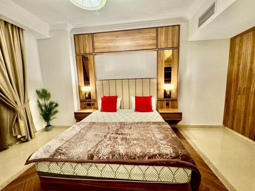 a bedroom with a large bed with red pillows at JSCOM GRAND Residence in Dubai