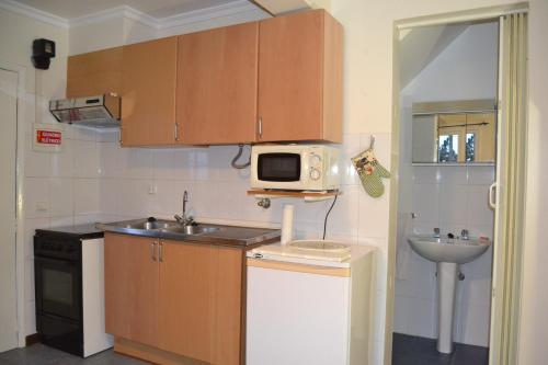 a small kitchen with a microwave and a sink at Rib Brava Garden Apartment in Ribeira Brava