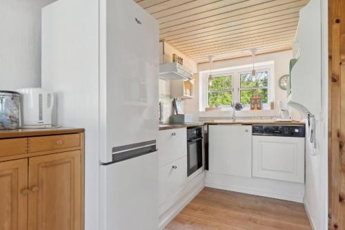 a kitchen with white appliances and a wooden ceiling at The Cozy Cottage in Hirtshals
