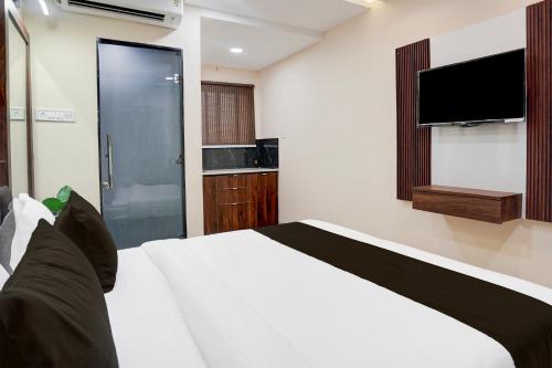 a bedroom with a white bed and a flat screen tv at Hotel O Lakshya in Indore